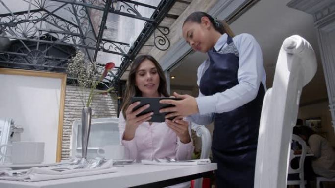 女商人在平板电脑上看菜单时在酒店的餐厅吃饭