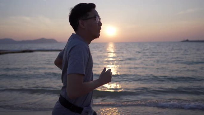 亚洲男子在日落时在沙滩上奔跑