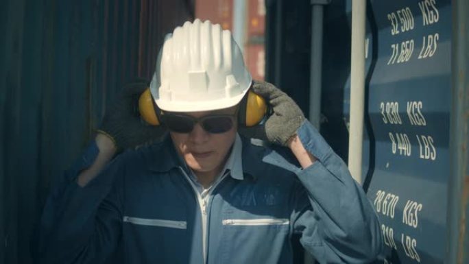 男工人戴上安全耳罩在港口工作前准备慢动作