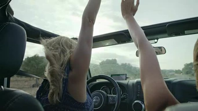 女孩们在越野车里玩得开心。手放在天窗上。