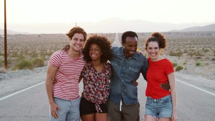 四个快乐的朋友站在沙漠高速公路上，特写
