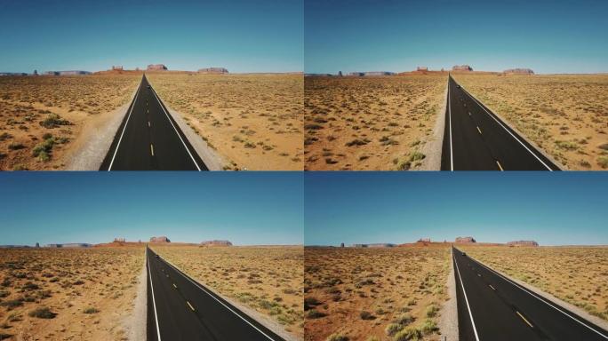 无人机跟随汽车沿着纪念碑谷的标志性美国沙漠公路行驶，并带有大悬崖山脉的天际线。