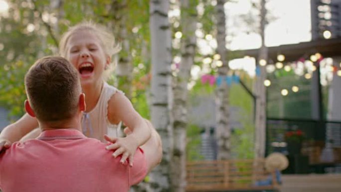 可爱的小女孩跑向父亲，他站在膝盖上拥抱她。在阳光明媚的夏日里，在花园里玩耍，家庭幸福的时刻。