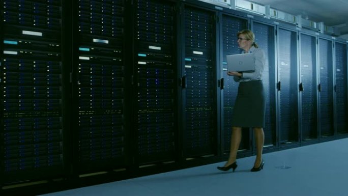在数据中心，女性IT专家沿着一排操作服务器机架行走，检查正常运行。现代高科技电信运营数据中心。