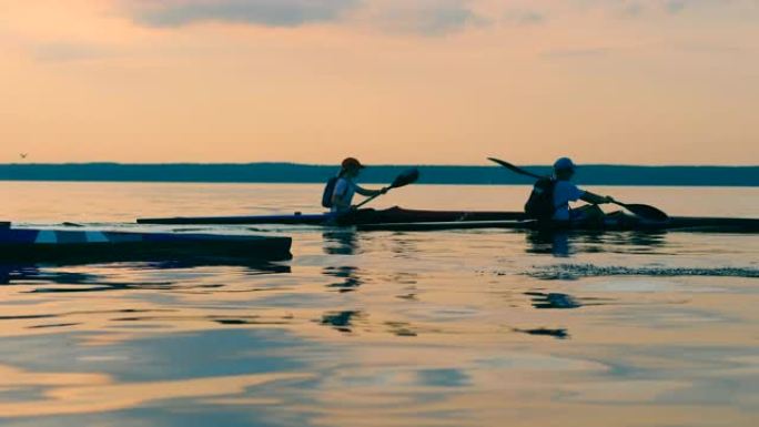 划桨手在皮划艇穿越日落湖的侧视图