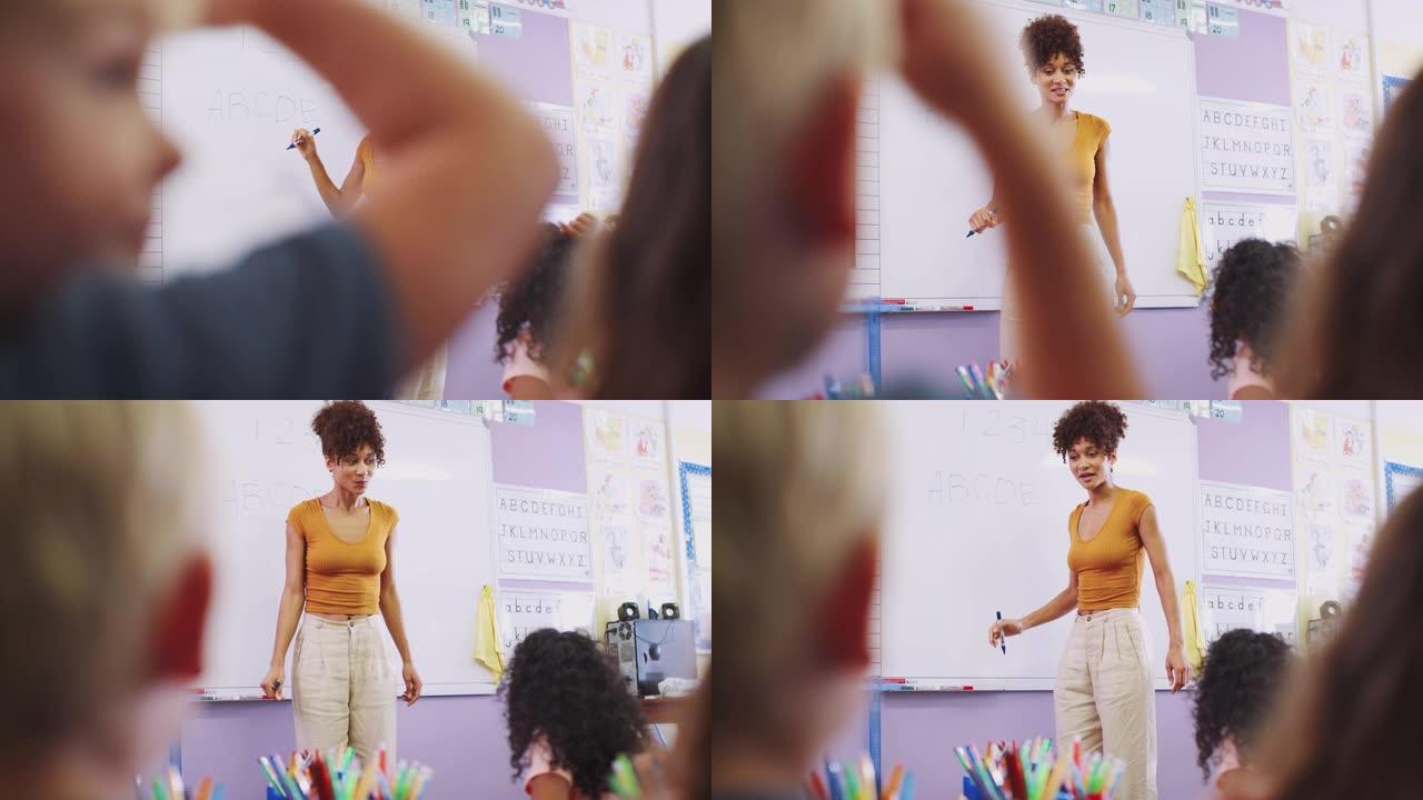 女老师站在白板上给小学生上课在学校教室里