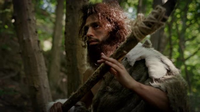 原始穴居人的肖像在史前森林中穿着动物皮和毛皮，用石尖矛狩猎。史前尼安德特人猎人准备在丛林中投掷长矛