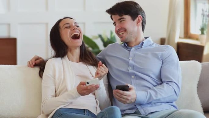 幸福的夫妇笑着拿着智能手机分享有趣的新闻