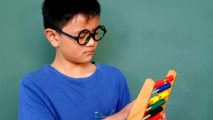 4k学校教室里用算盘解决数学问题的亚洲男生的前视图