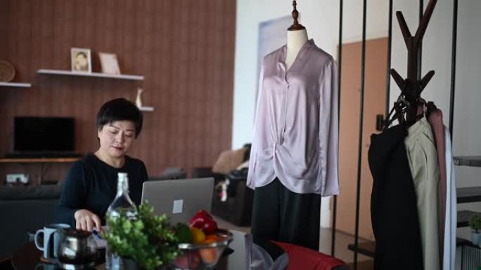 一名亚洲中国中年妇女在她的餐厅拍摄和录制用于在线购物业务目录的布