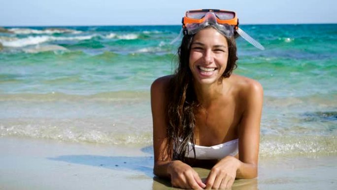美丽的年轻女子在海上微笑，穿着泳衣戴着潜水面具快乐。