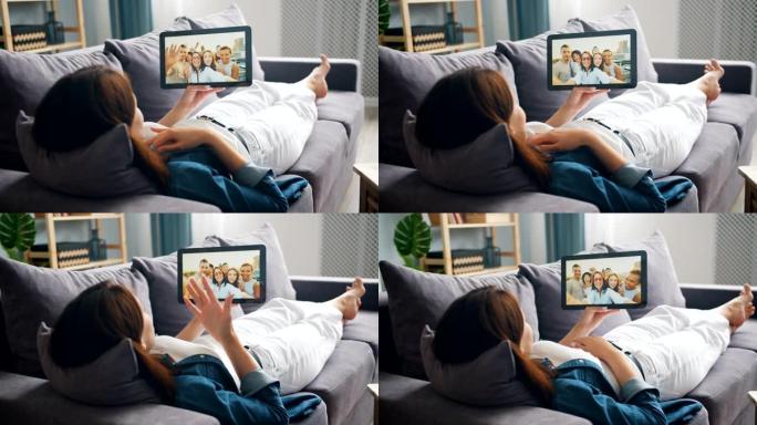 年轻女子用平板电脑与躺在沙发上的朋友聊天进行视频通话