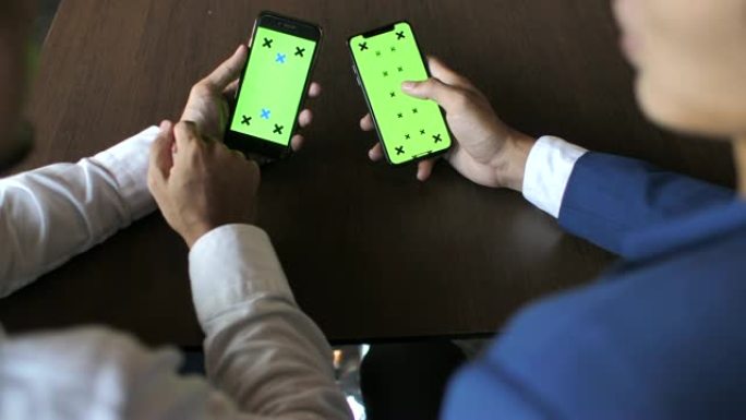 两人使用带有绿屏的智能手机交谈，手握，水平