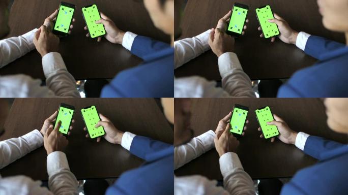 两人使用带有绿屏的智能手机交谈，手握，水平