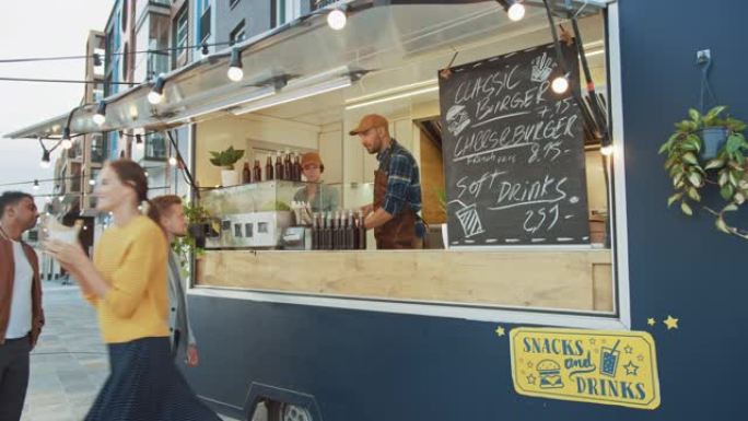 Food Truck员工将新鲜制作的美食汉堡交给排队的快乐年轻男女。街头食品卡车在现代时髦的社区户外