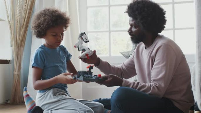 黑色中年父子坐在地板上一起组装机械套件玩具，特写，侧视图