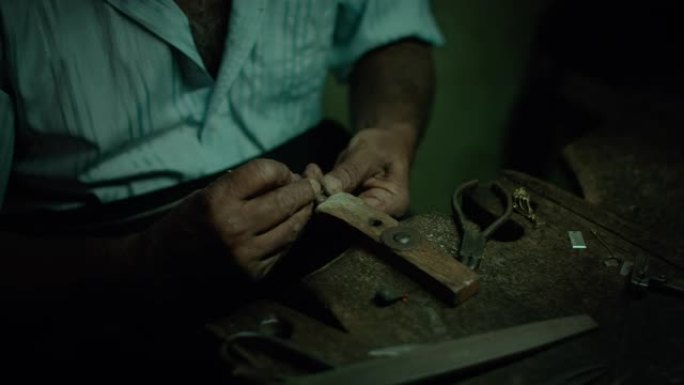 正宗的手工珠宝大师在他的车间里用锉刀/刨丝器做最后的笔触，制作一种新的原创产品。手部特写