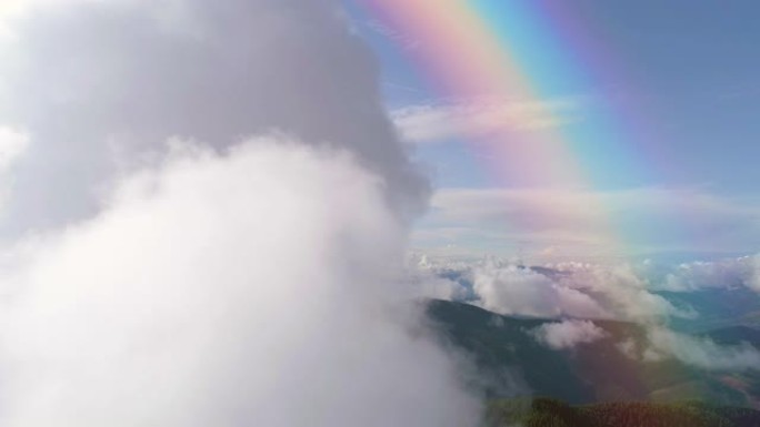 彩虹背景下群山上空的云层飞行。过度下垂