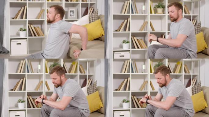 男子在家庭锻炼期间蘸沙发和使用健身跟踪器