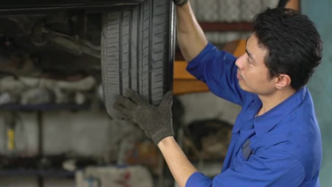 4k: 男性机械师在汽车修理厂检查轮胎。