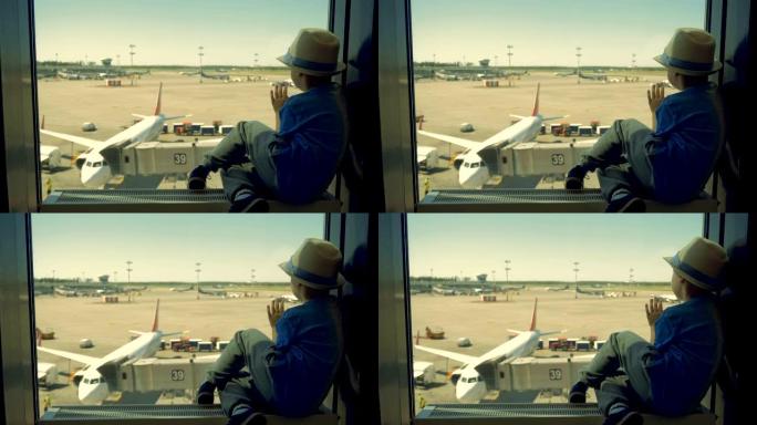 看飞机装载的孩子，特写。一个男孩坐在机场大楼里，透过窗户看着飞机。