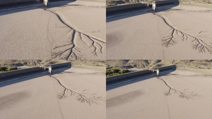 由于气候变化和全球变暖造成的干旱，一个饱受摧残的农民走过干燥大坝的破裂的泥面的4k高鸟瞰图