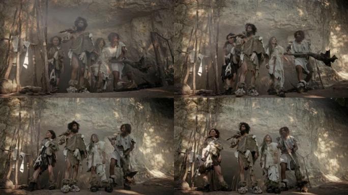 由四个狩猎采集者组成的部落，他们戴着动物皮，拿着石尖工具，在洞穴入口处摆姿势。两个成年男性和两个女性