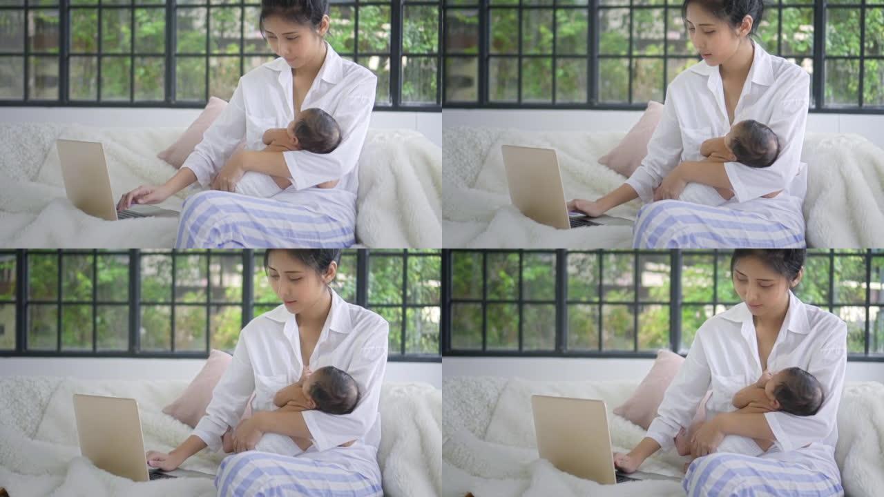 母亲使用笔记本电脑并将男婴抱在怀里，慢动作