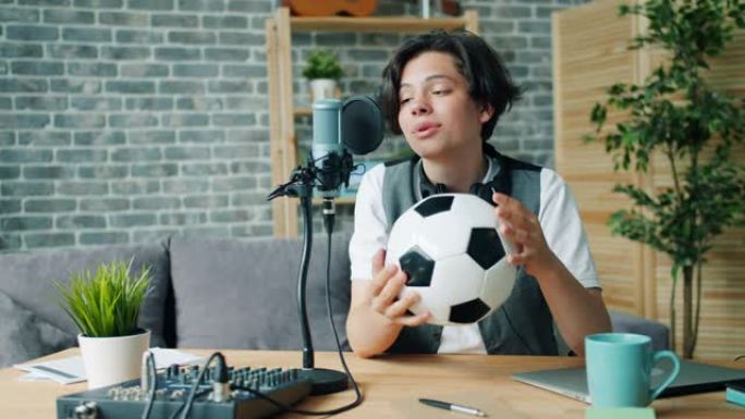 快乐的孩子录制关于足球拿着球用麦克风说话的音频