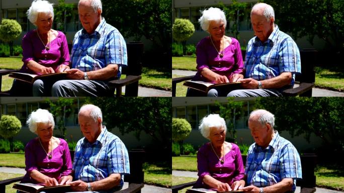 活跃的高加索高级夫妇在养老院4k花园里看相册的前视图