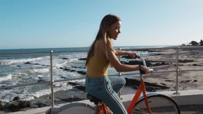 一个高加索女孩骑自行车海边的侧视图