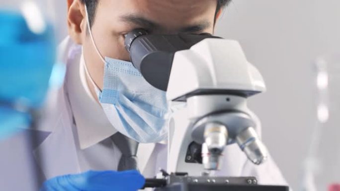 领导亚洲男性科学家观察显微镜焦点从病毒到实验室技术研究到冠状病毒或Covid-19。在生命科学实验室