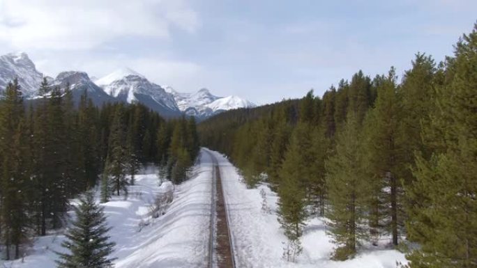 沿着铁路空中飞行，穿过寒冷的山脉下的树林