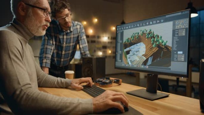 晚上，创意中年视频游戏开发人员在具有屏幕3D视频游戏级别设计的台式计算机上工作，并与使用平板电脑的年