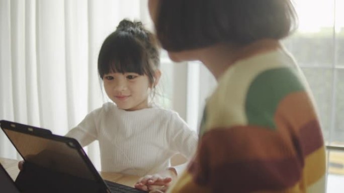 年轻的母亲在家工作，女儿在桌子上。