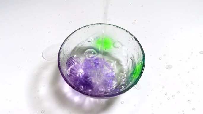 将水倒入带有紫色花朵的玻璃碗中。