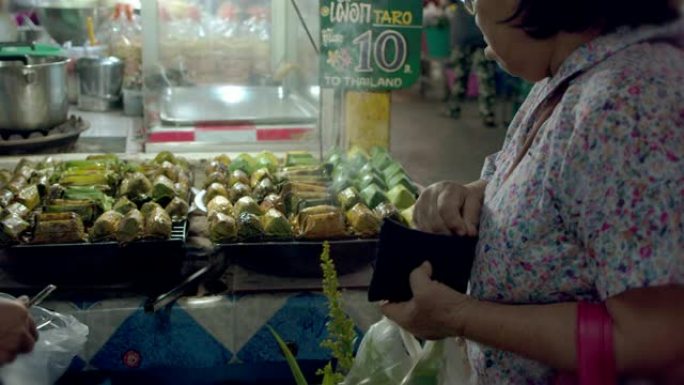 亚洲高级妇女在农贸市场购买泰国甜点