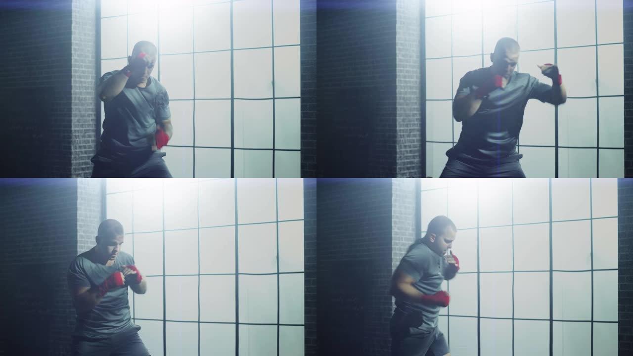 强壮英俊的男拳击手正在阁楼健身房锻炼，墙上贴着励志海报。男性运动员正在空中练习拳击。他很认真，精力充