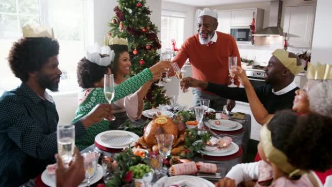 黑人祖父站在家里的圣诞餐桌前演讲和敬酒