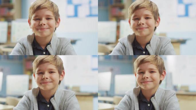 一个可爱的小男孩坐在他的课桌前，快乐地微笑着。聪明的小男孩，带着迷人的微笑坐在教室里。特写镜头