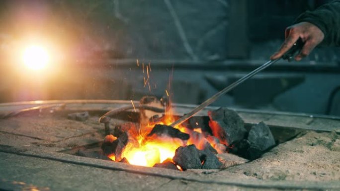 铁匠用金属扑克移动煤。