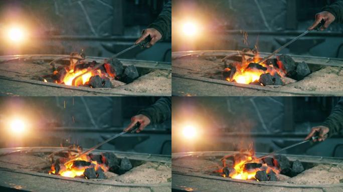 铁匠用金属扑克移动煤。