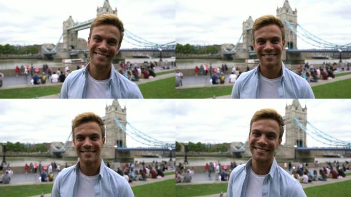 高加索游客在镜头前微笑，在背景下的伦敦桥