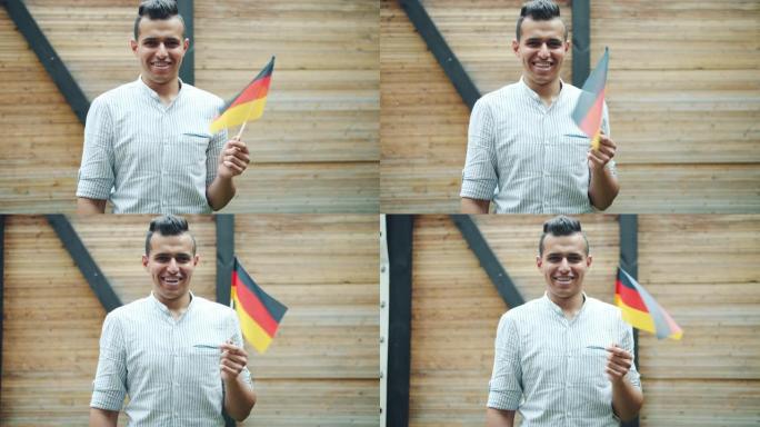 年轻的阿拉伯人在城市街道上挥舞着德国国旗并在户外微笑的肖像