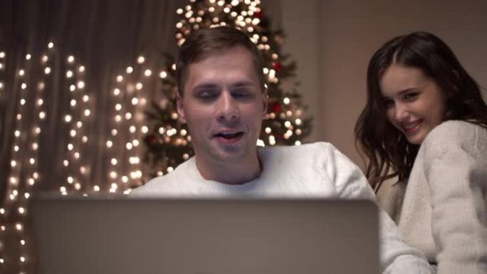 年轻夫妇坐在床上看卧室里的圣诞照片。