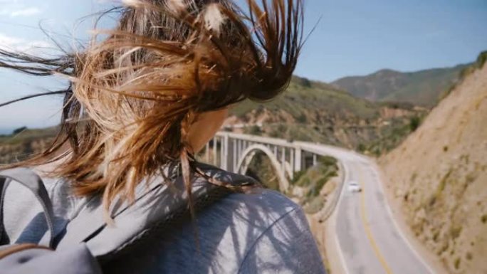 特写后景年轻的旅游女子，头发在强风中飞翔，在大苏尔比克斯比大桥观看令人惊叹的景色。