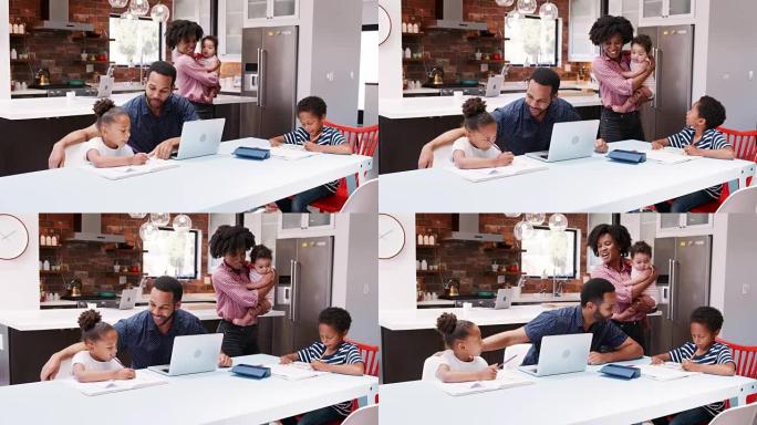 父亲帮助孩子做家庭作业，而母亲在家里的厨房里抱着小女儿-慢动作拍摄