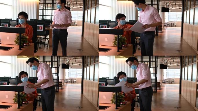 2位亚洲华裔同事在办公室用新的握手方式互相问候，戴着防护面罩