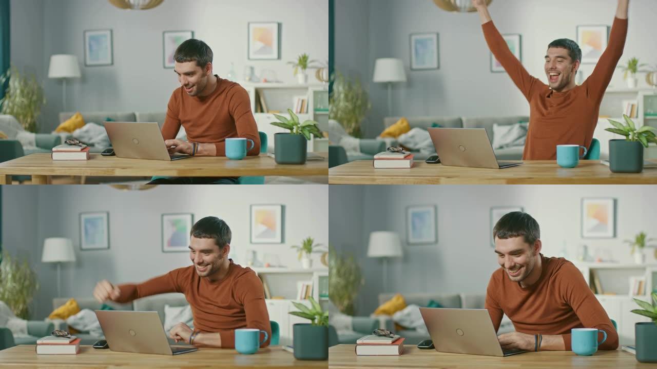 成功的微笑男子的肖像在家里的笔记本电脑上工作，收到好消息，并高兴地庆祝他的胜利是肯定的手势。在家庭办