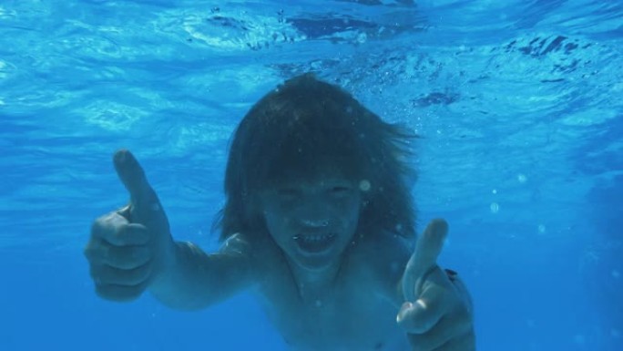 男孩在游泳池游泳时竖起大拇指